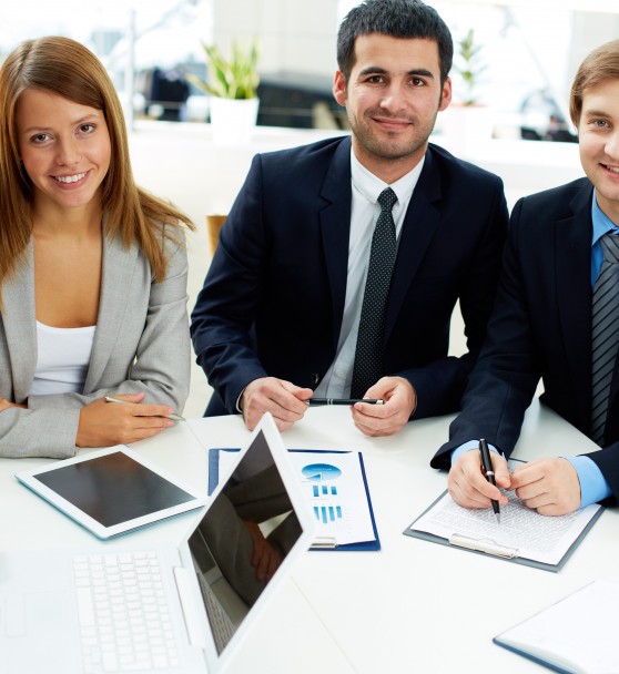 Image of business partners sitting at workplace and looking at camera